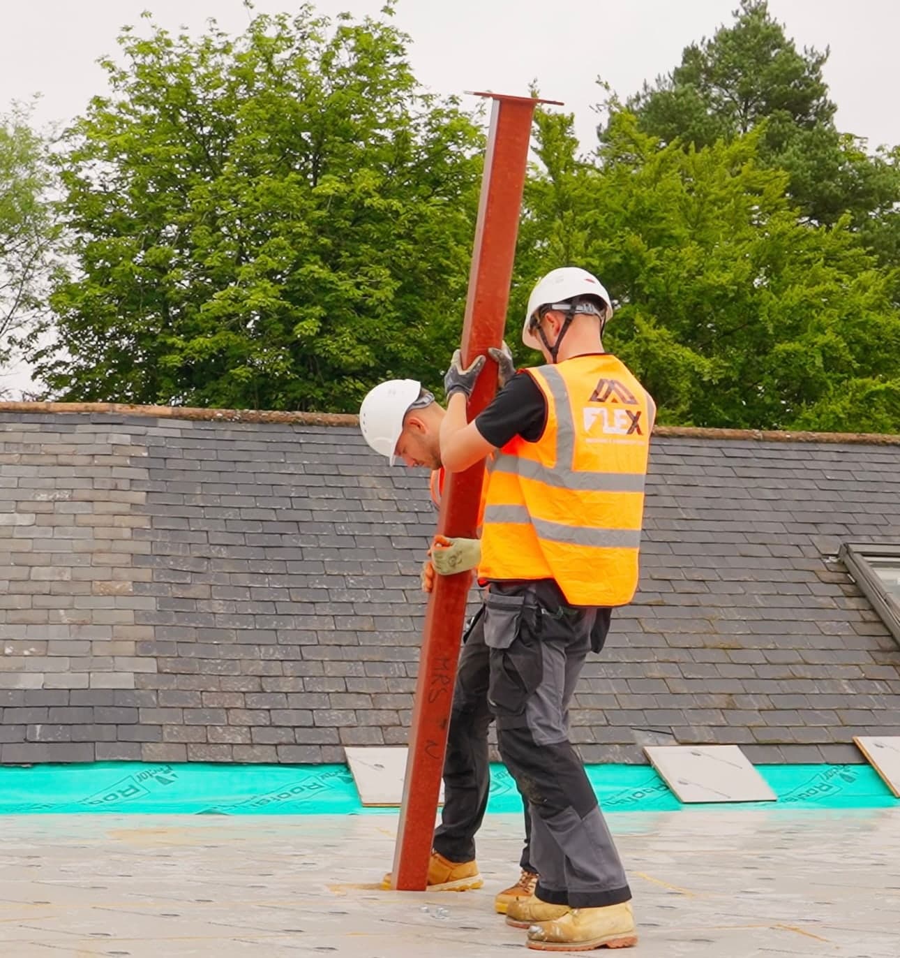FLEX Building Co. team installing a steel post on a roof